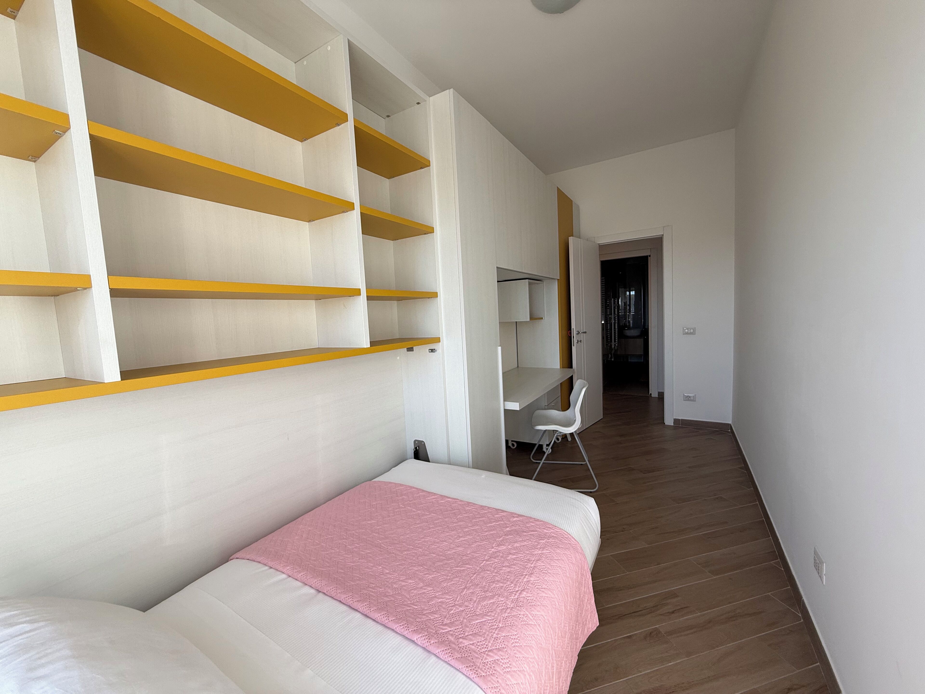 A bedroom with a bed, a desk, and a chair.