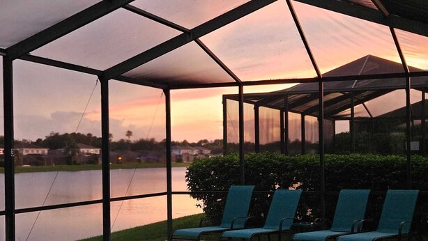 A pool area with a covered seating area and a view of a lake.