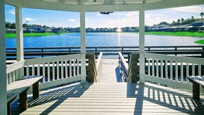 A covered wooden deck with white railings overlooking a body of water.