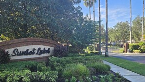 A landscaped area with a sign reading "Sunset Lakes".
