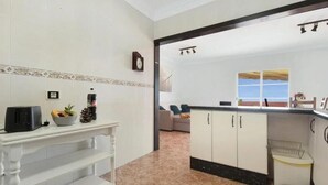 Eine Küche mit weißen Schränken, einem Einbauherd und einem Fenster mit Blick auf einen Balkon.