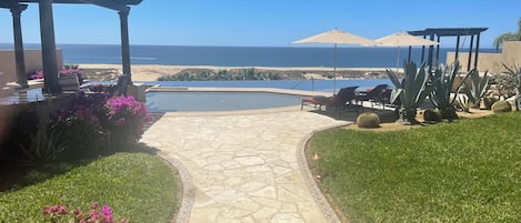 A stone pathway leading to a pool with a view of the ocean.