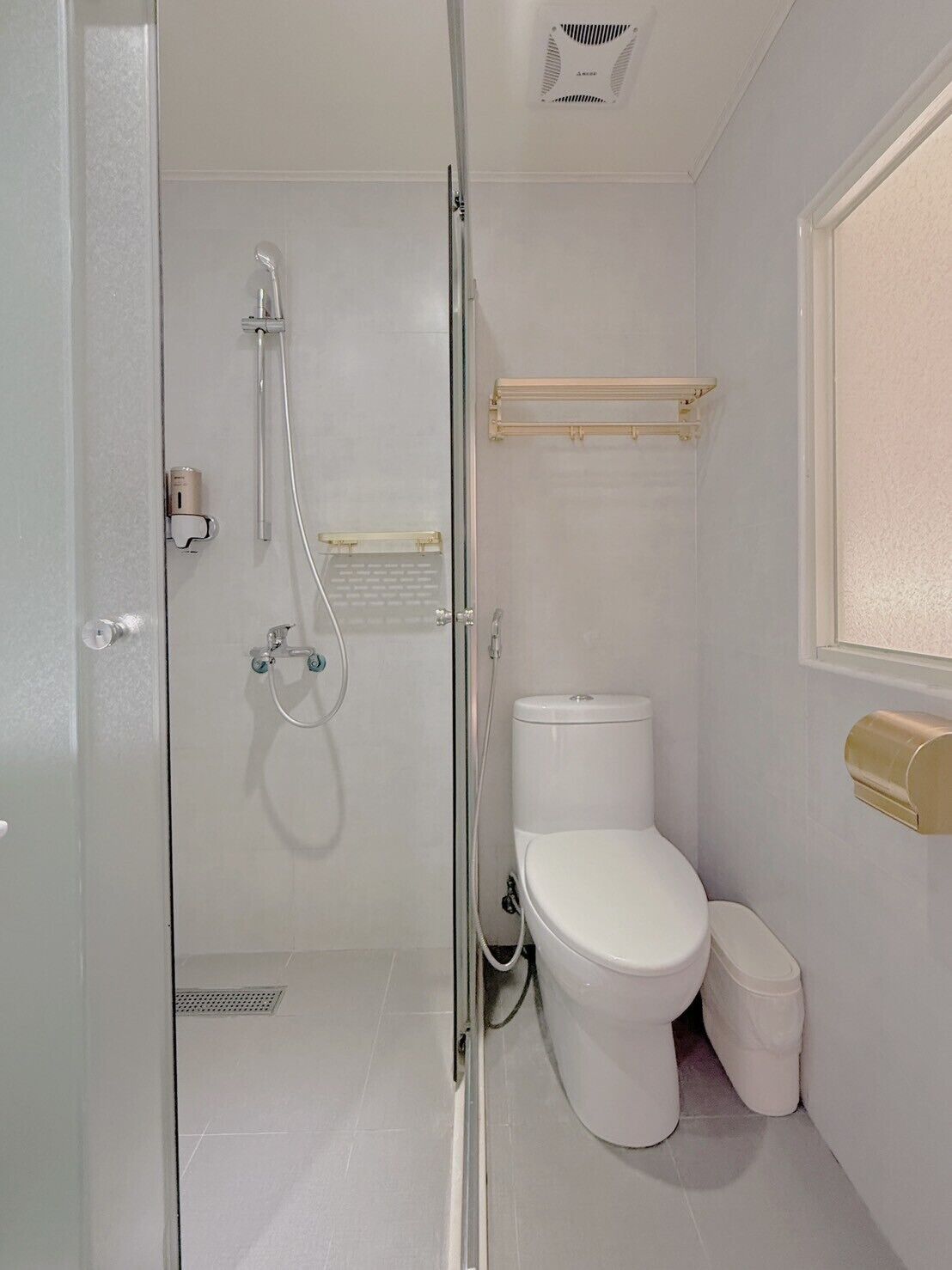 A small, modern bathroom with a glass shower enclosure, a toilet, and a bidet.