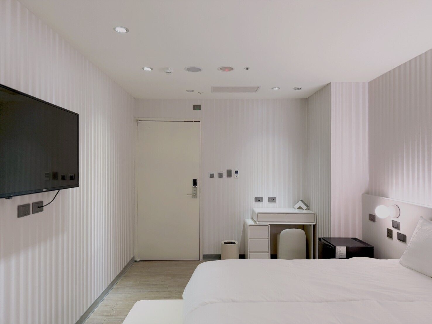 A modern hotel room with a large bed, a desk, a television, and a bathroom.