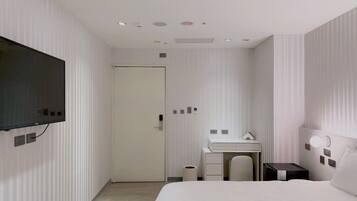 A modern hotel room with a large bed, a desk, a television, and a bathroom.