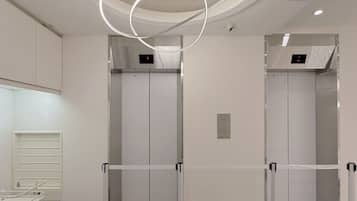 Un área de ascensores moderna con un lámpara circular en el techo, dos ascensores y un mostrador de recepción blanco.