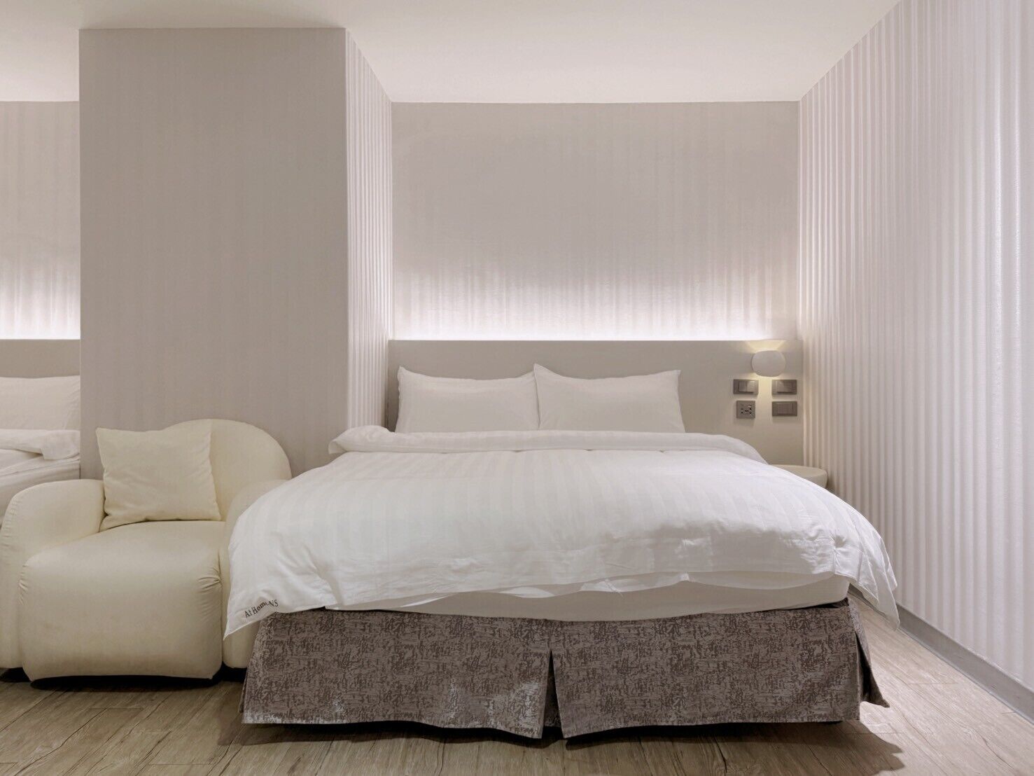 A modern bedroom with a large bed, a bedside table, and a chair.