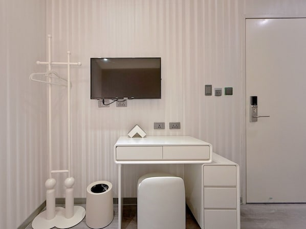 Un bagno moderno e minimalista con un mobile lavabo bianco, una televisione a muro e una porta con serratura a chiave.