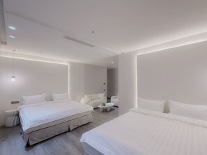 Una camera d'albergo moderna con un letto grande, un letto più piccolo, due poltrone e un tavolino.