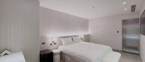 A modern bedroom with a large bed, bedside tables, a wardrobe, and a built-in heater.