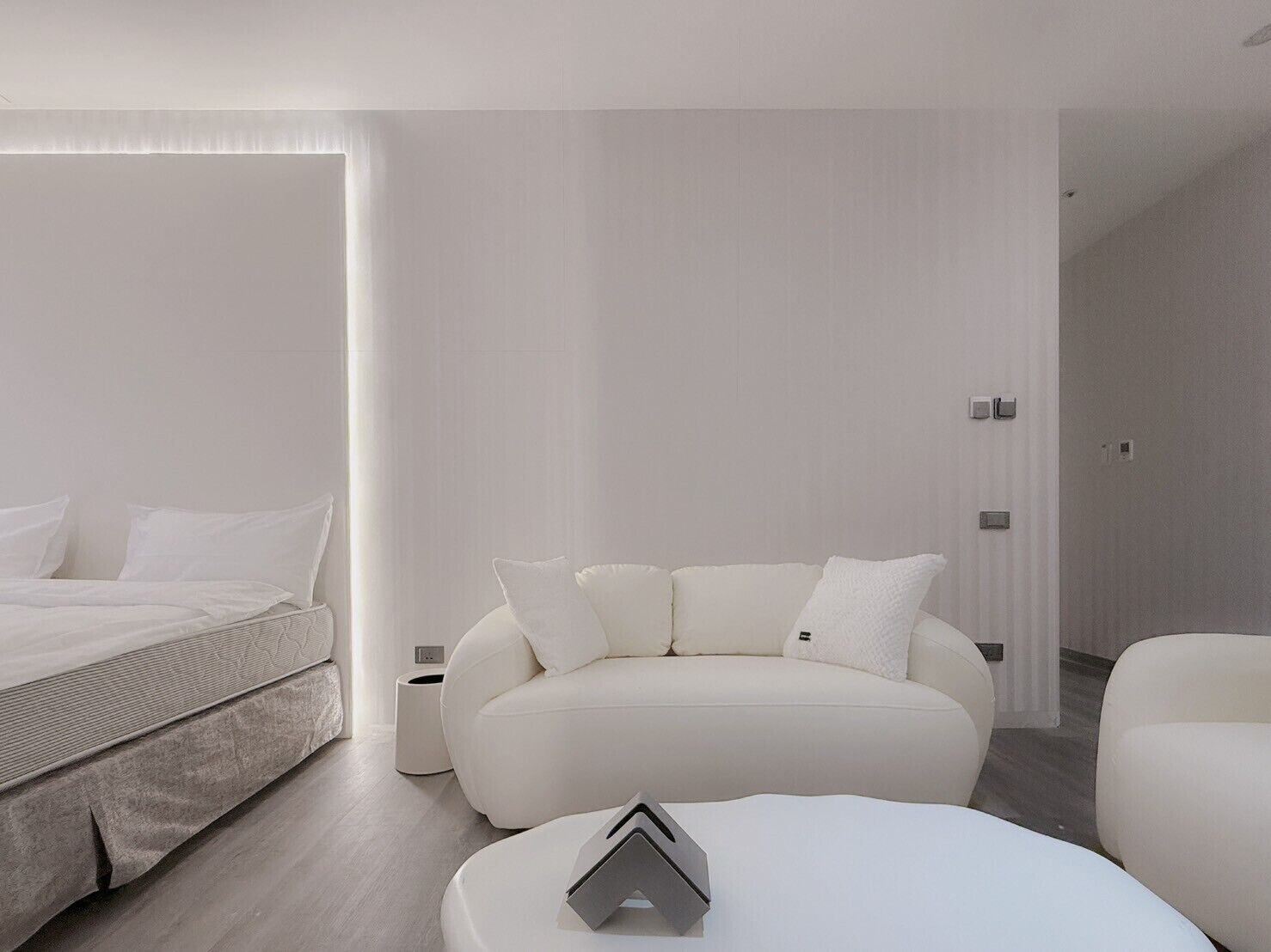Una camera da letto moderna e minimalista con un letto, un divano e un tavolino.