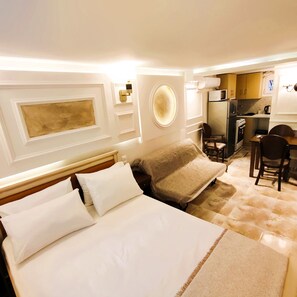 Ein Hotelzimmer mit Bett, Sessel, kleinem Tisch und einer Küchenzeile.
