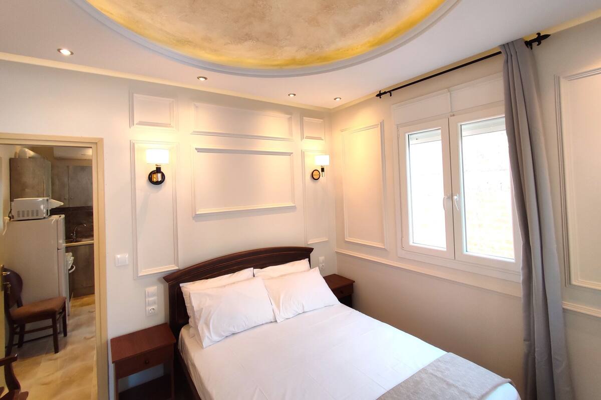 A hotel room with a bed, bedside tables, a wardrobe, a mirror, and a window with curtains.