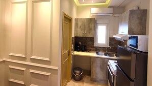 A compact kitchen with white cabinetry, a built-in microwave, and a small window above the sink. - Villa Miltiadis GreeceFiloxenia (Volos)