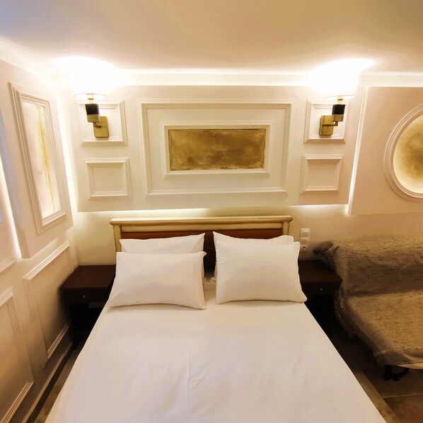 A hotel room with a large bed, two bedside tables, a headboard, and a round mirror. - Villa Miltiadis GreeceFiloxenia (Volos)