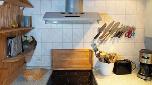 A kitchen with a stove, toaster, coffee maker, and various utensils on the wall. - Vacation home with great garden and kitchen in Bruinisse near Renesse private park (Bruinisse)
