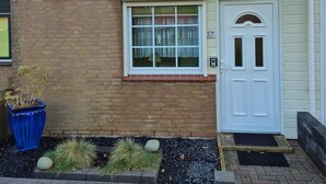 A small brick house with a tiled roof, a white door, and a window with a white frame. - Vacation home with great garden and kitchen in Bruinisse near Renesse private park (Bruinisse)