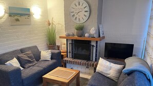A cozy living room with two grey sofas, a wooden coffee table, a fireplace, and a wall clock. - Vacation home with great garden and kitchen in Bruinisse near Renesse private park (Bruinisse)