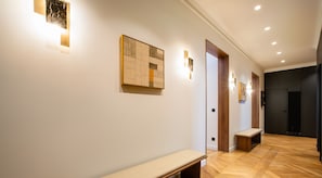 Un pasillo con un banco, una obra de arte en la pared e iluminación empotrada.