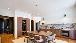 A modern kitchen with a marble countertop, wooden cabinets, and a dining area with a wooden table and chairs.