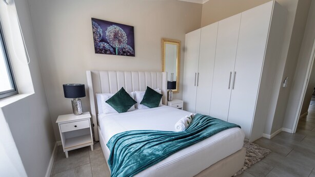 Un dormitorio con cama, mesitas de noche, espejo y armario.