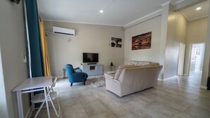 Una sala de estar con televisor, sofá y una pequeña mesa con sillas.