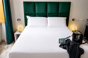 A bed with a green upholstered headboard, white bedding, and two bedside lamps.
