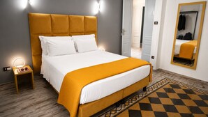 Una cama con cabecera, lámparas de noche, un espejo y un suelo estampado.