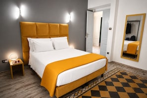 A bed with a headboard, bedside lamps, a mirror, and a patterned floor.
