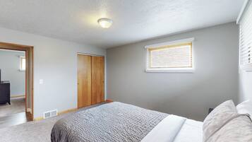 A bedroom with a bed, a wardrobe, a window with blinds, and a ceiling light.