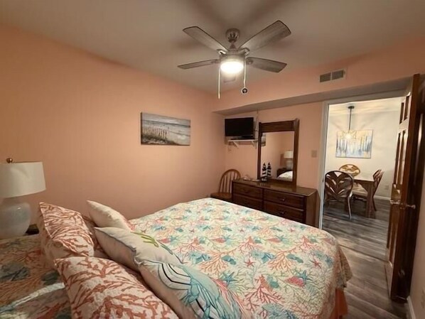 A bedroom with a bed, dresser, and a ceiling fan.