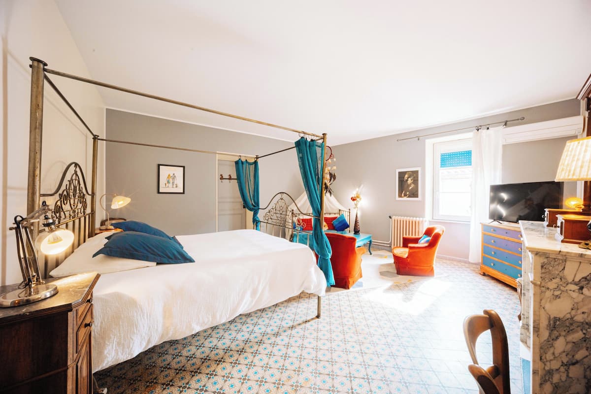 A bedroom with a bed, bedside table, lamp, and a chair.