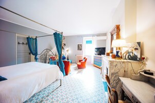 Una habitación de hotel con cama, una silla, escritorio y baño.
