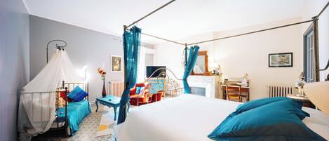 Een slaapkamer met een bed, nachtkastje, stoel, bureau en een raam met gordijnen.