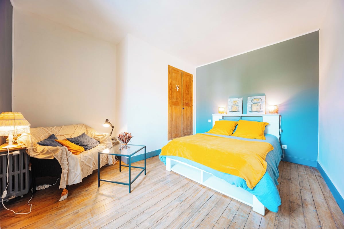 A bedroom with a bed, bedside table, lamp, and a wooden wardrobe.