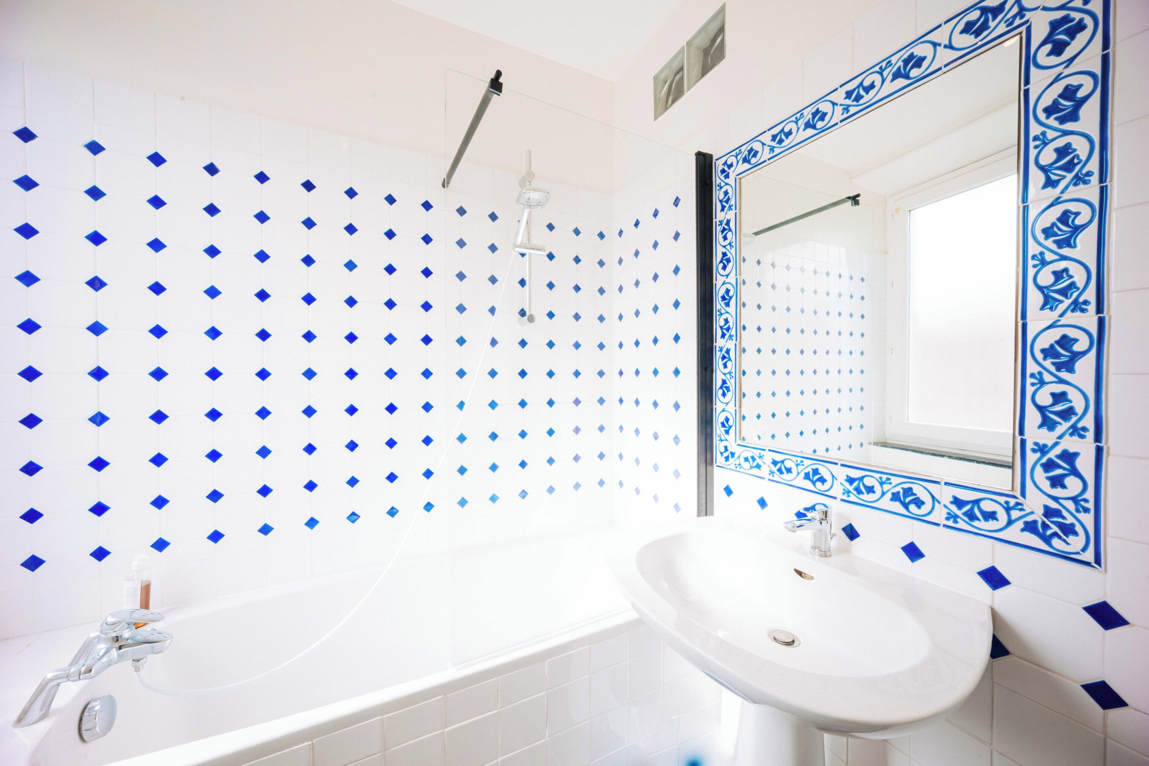 Een badkamer met een witte badkuip, een wit wastafelmeubel en een spiegel met decoratieve lijst.