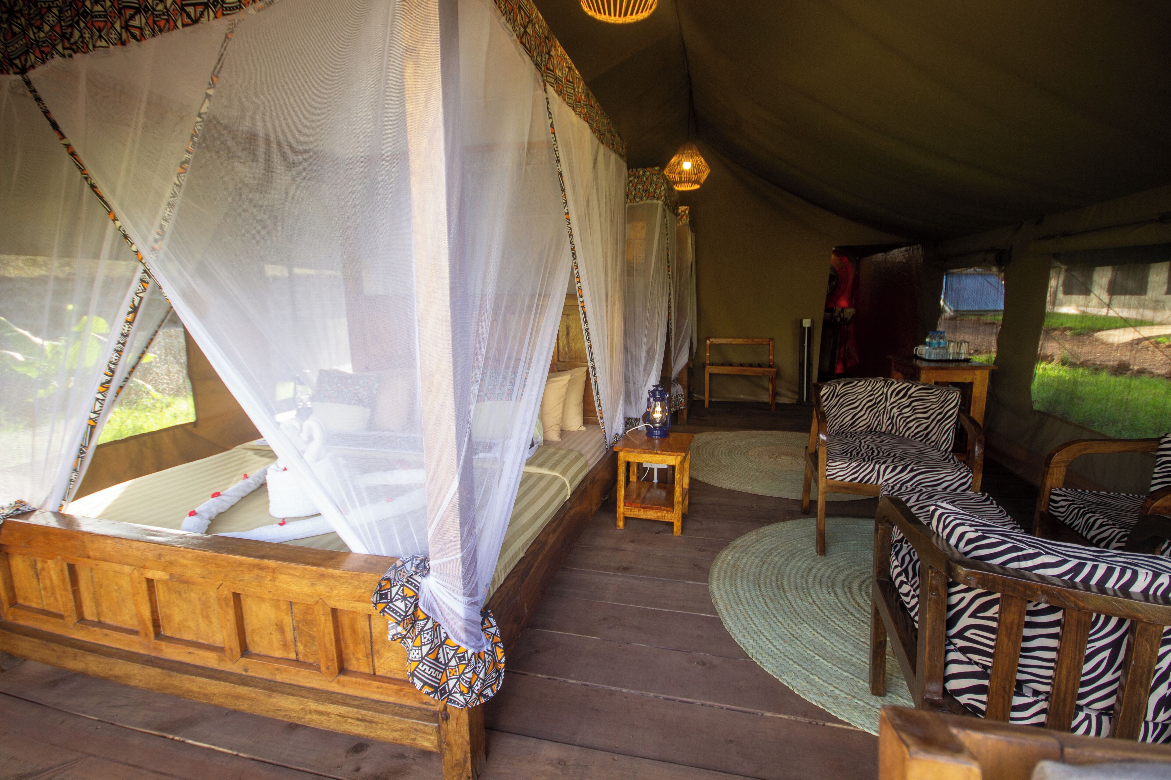 A room with a wooden bed, a zebra-patterned sofa, a small wooden table, and a hanging light fixture.