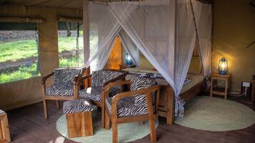 Ein Zelt mit Bett, Zebrastuhl-Möbel und Moskitonetz.