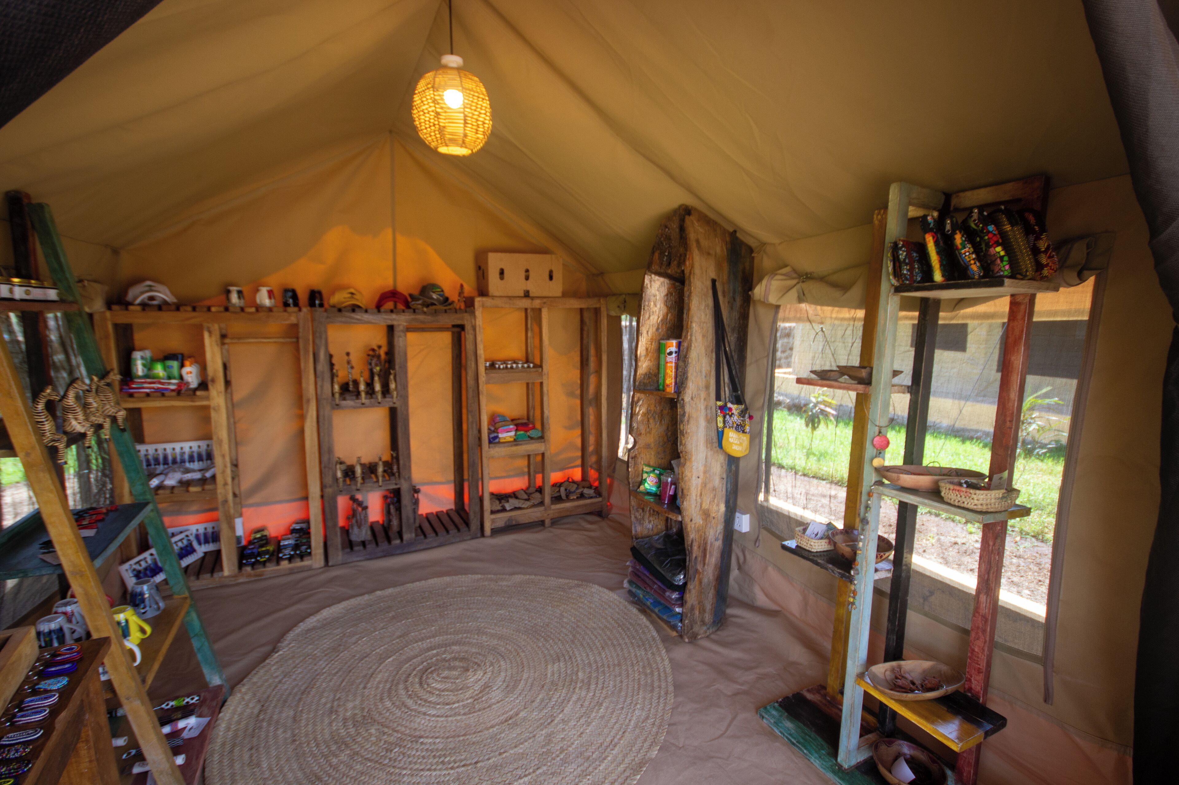 A tent with a circular woven mat in the center, shelves with various items, and a hanging light fixture.