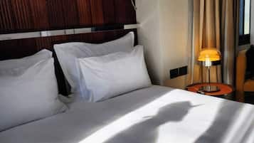 Ett hotellrum med en stor säng, två kuddar, ett nattduksbord med en lampa och en sänggavel i trä.