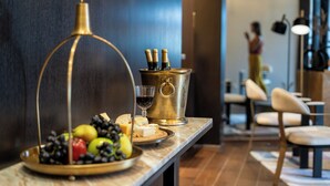 A bar area with a marble countertop, a gold-colored wine cooler, and a selection of cheeses and fruits. - Fiori 41 (Tel Aviv)