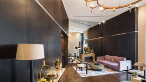 A modern living room with dark wood flooring, a large sofa, a coffee table, and a lamp. - Fiori 41 (Tel Aviv)