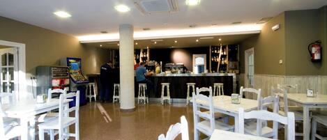 A restaurant with white tables and chairs, a bar area, and a counter.