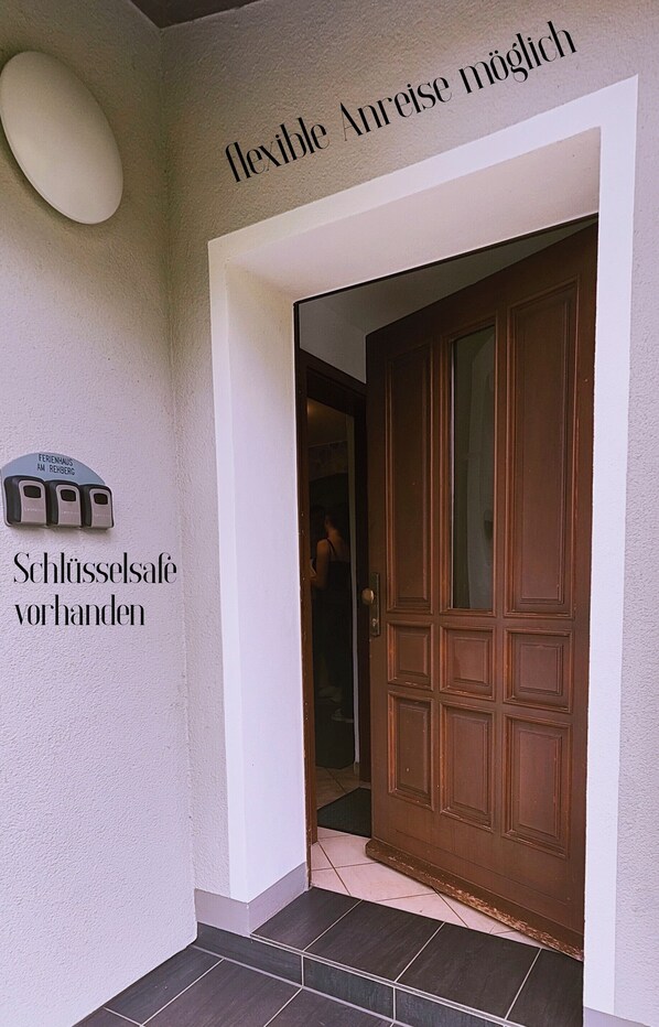 A hotel entrance with a sign indicating 'flexible Anreise möglich' and 'Schlussssafe vorhanden'.