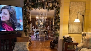 A cozy living room with a television, a fireplace, and a dining area decorated for the holidays. - Yellow Daisy Bed and Breakfast (Dahlonega)