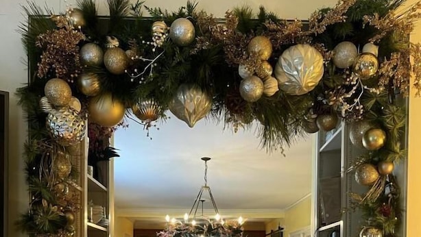 A dining area with a chandelier, a Christmas tree, and a white chair. - Yellow Daisy Bed and Breakfast (Dahlonega)
