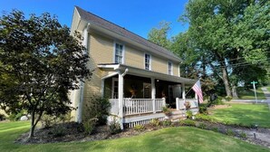 A two-story house with a porch, a flag, and a well-maintained lawn. - Yellow Daisy Bed and Breakfast (Dahlonega)