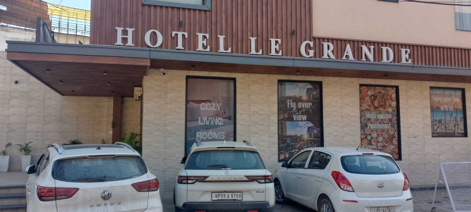 A hotel named "HOTEL LE GRANDE" with a sign indicating "COZY LIVING ROOMS" and "FLY OVER VIEWS."