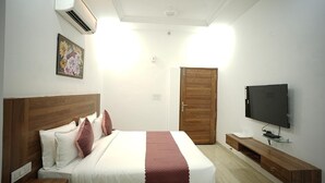 Un dormitorio con cama, televisor, armario y aire acondicionado.