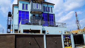 Ein Hotel mit blauer und weißer Fassade, einem Balkon mit Metallgeländer und einem Schild, das die Wiedereröffnung anzeigt.